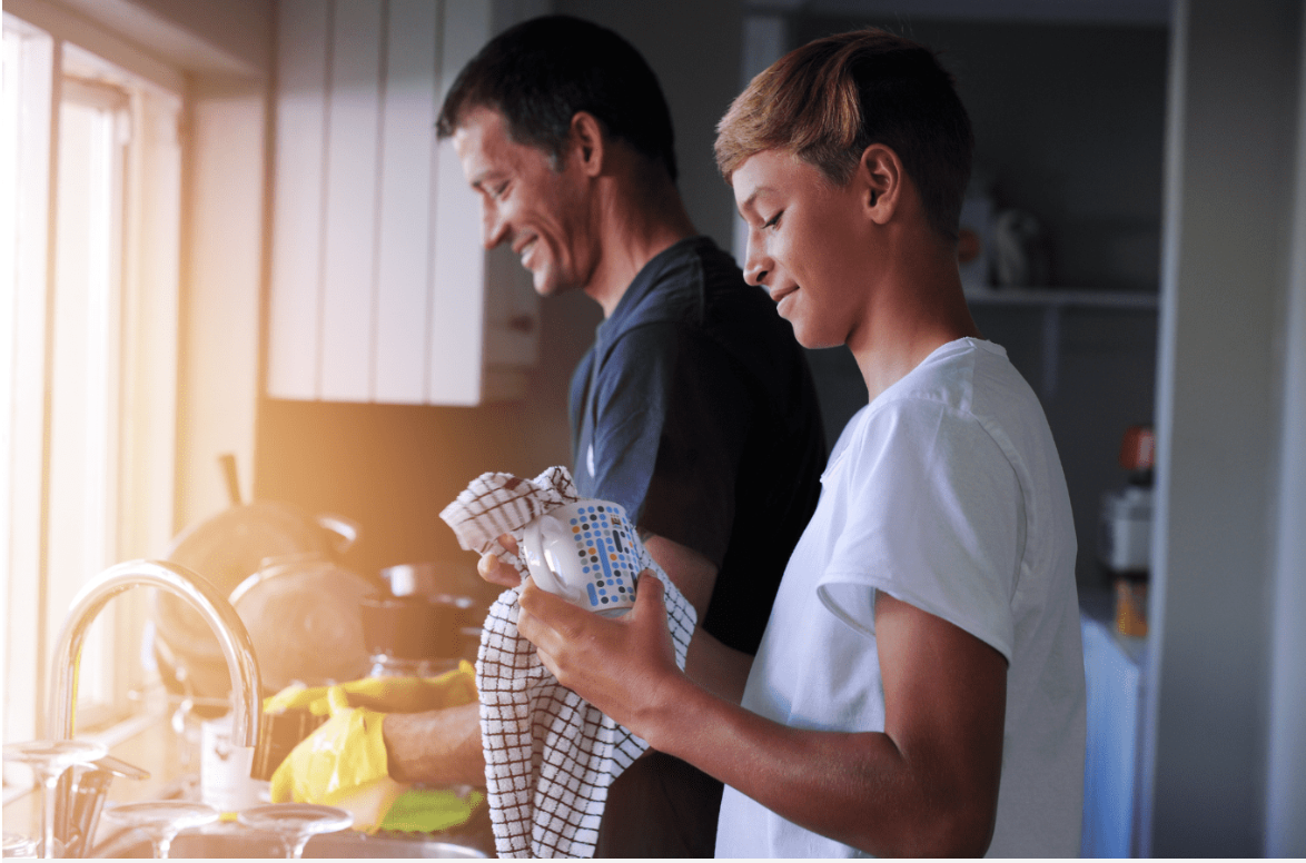 An adult and a child sharing the work of washing and drying dishes